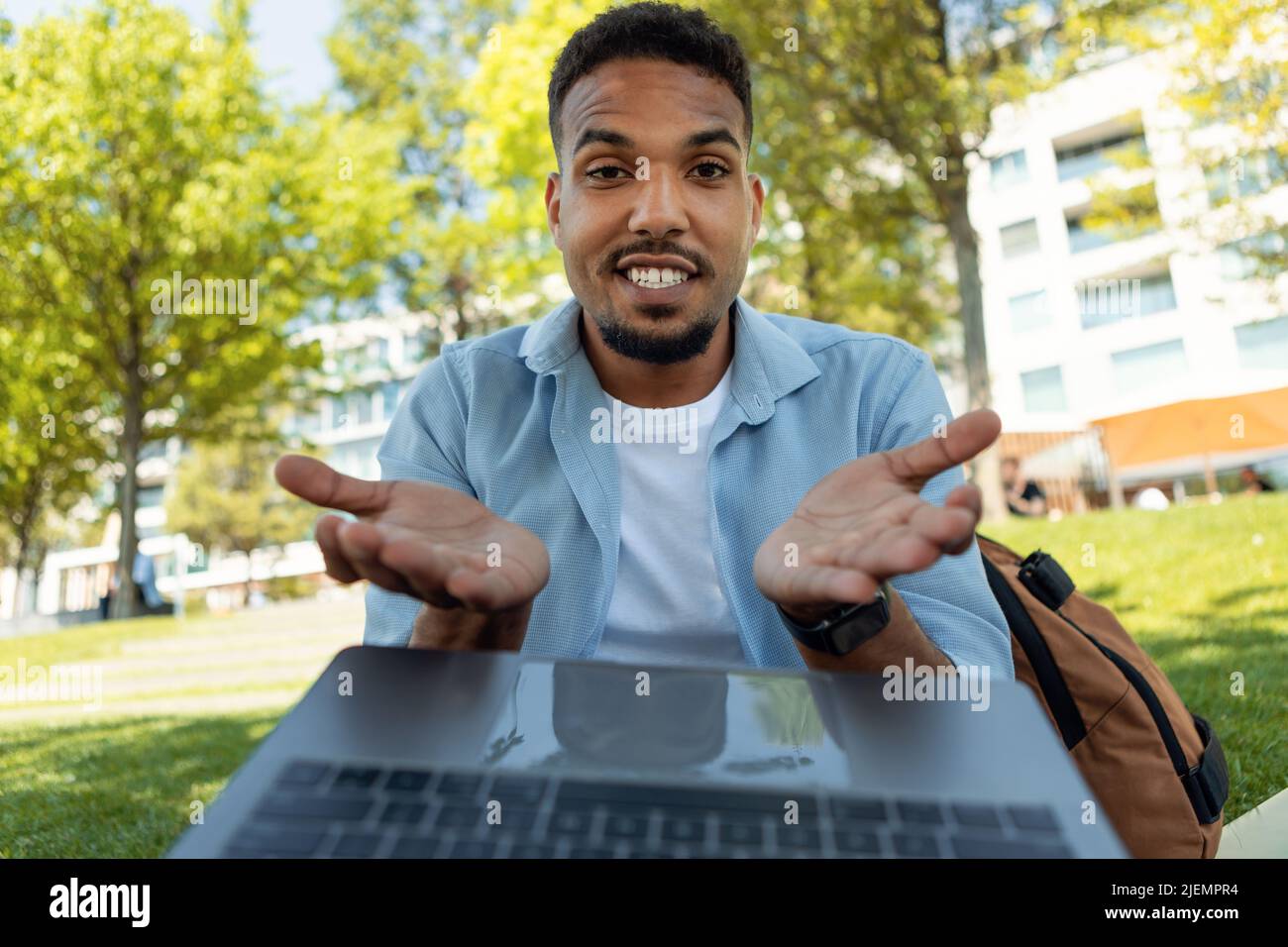 Excited young black guy talking to family or friend on laptop, gesturing at webcamera, sitting outdoors Stock Photo