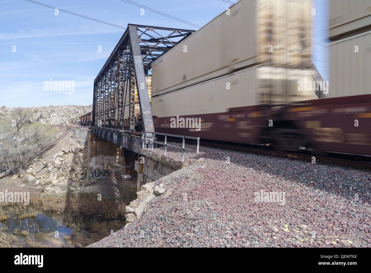 BNSF Railway train shown crossing a truss railroad bridge spanning the Mojave River shown in Victorville, California, USA on March 4, 2017. Stock Photo