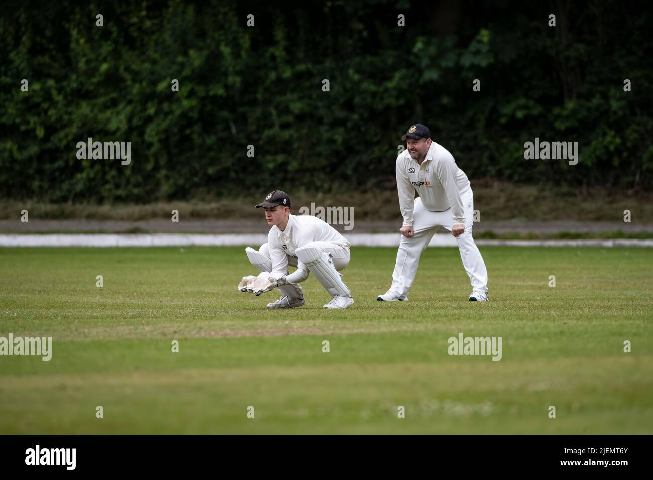 Wicket Keeper crouched behind the stumps with first slip fielder at a weekend village cricket match in Huddersfield, West Yorkshire, England Stock Photo