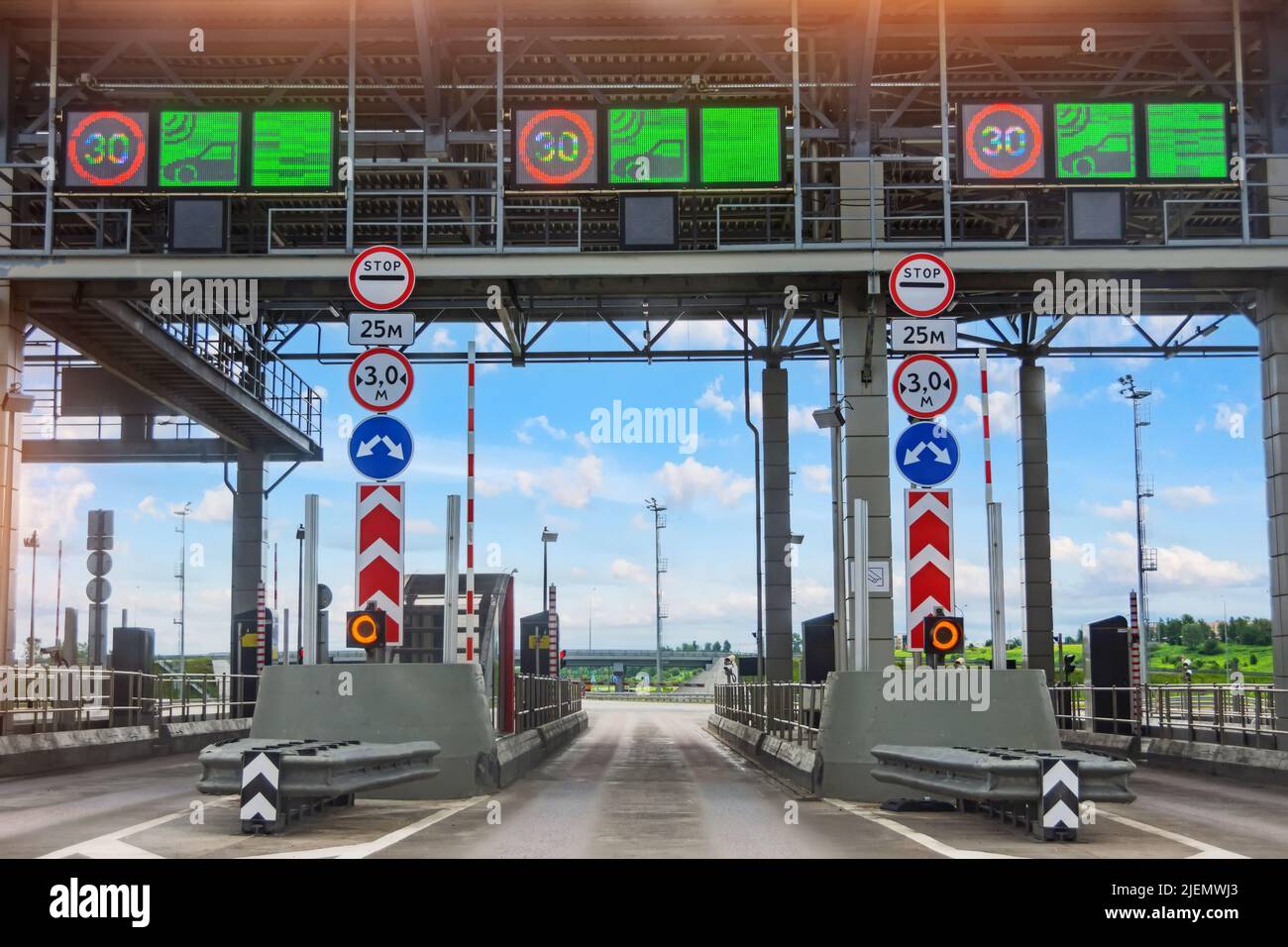 View without cars at the entrance to the toll road, limited by the barrier. Cashless payment transponder, speed limit signs Stock Photo