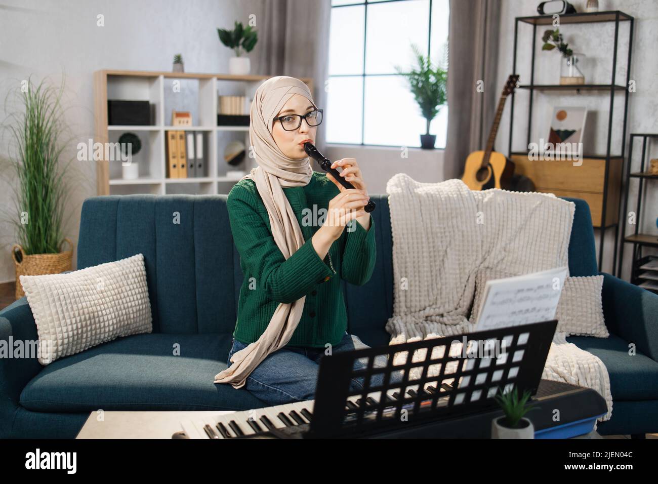 Portrait of young arab female with hijab playing on flute. Pretty ...