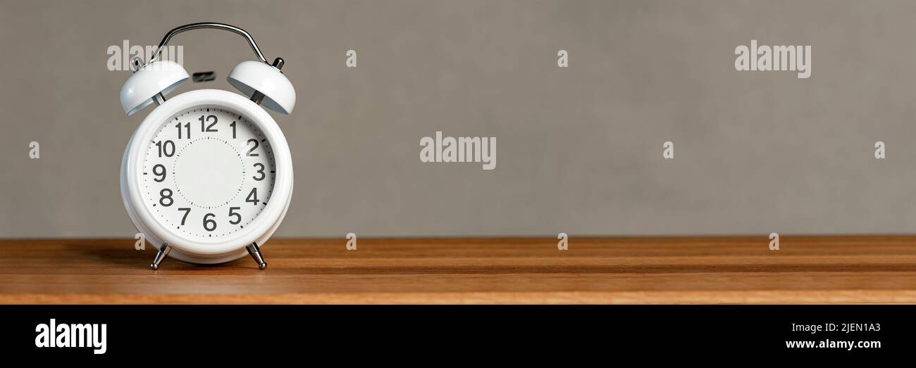 Alarm clock without arrows. White classic alarm clock on a wooden background without hands, space to insert text or copy. The concept of endless time Stock Photo