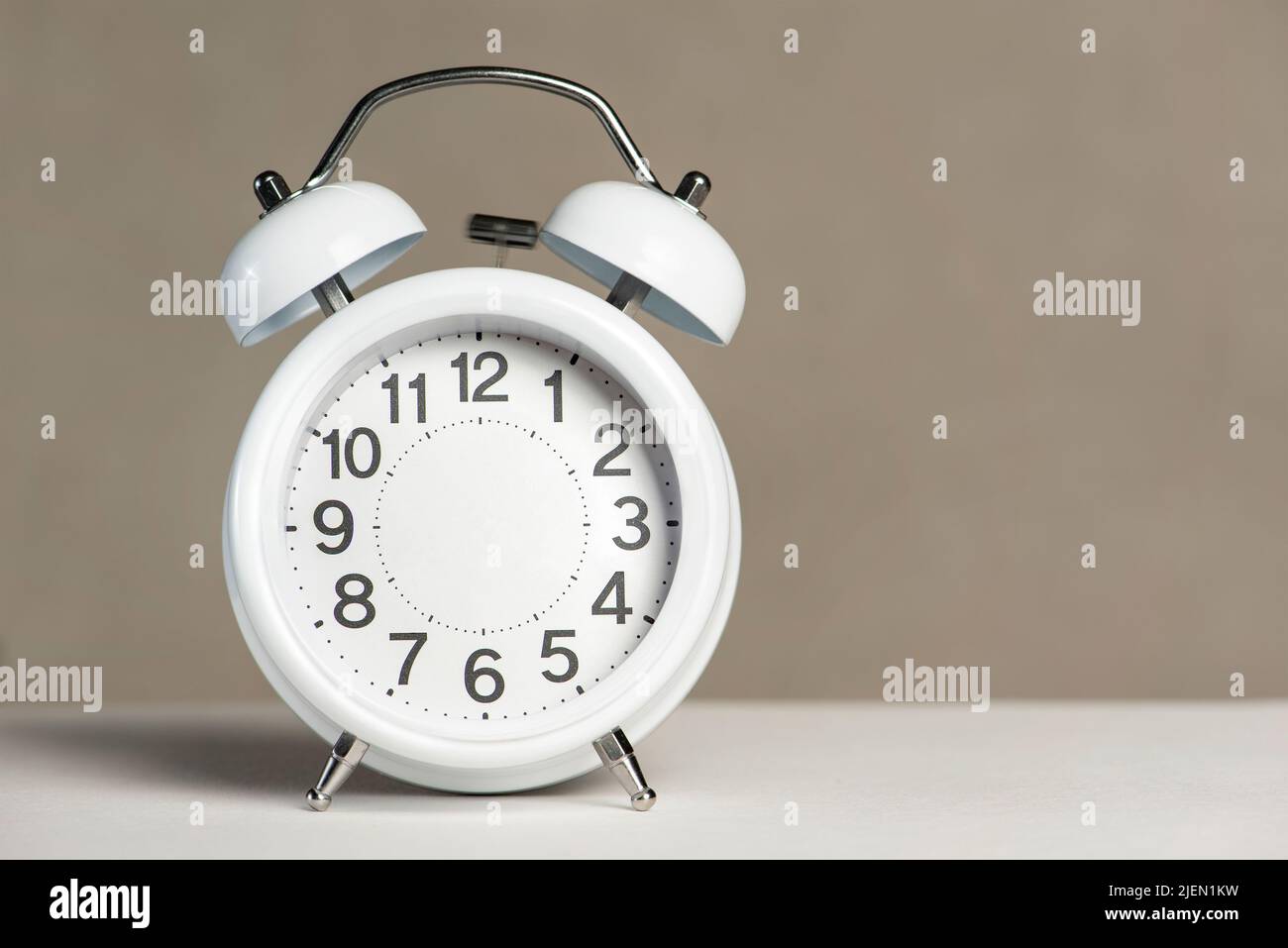 Alarm clock without arrows. White classic alarm clock on a white background without arrows, space to insert text or copy. The concept of endless time Stock Photo