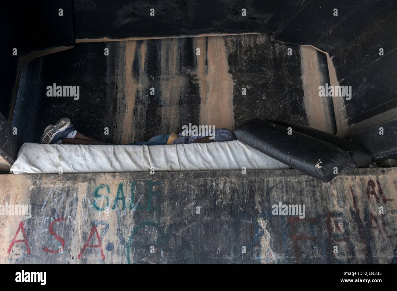 A young immigrant sleeps under a bridge in Melilla. In this Temporary Stay Center for Immigrants are concentrated the majority of people who on June 24 launched themselves on the Nador-Melilla border, which separates Morocco from Spain. This area located in North Africa is the last step of a long journey that thousands of people mainly from Africa and Asia make every year. Most of those who are in here are young men who still have to wait for a process of acceptance and integration to be able to cross the Mediterranean Sea and find work and a new way of life. Stock Photo