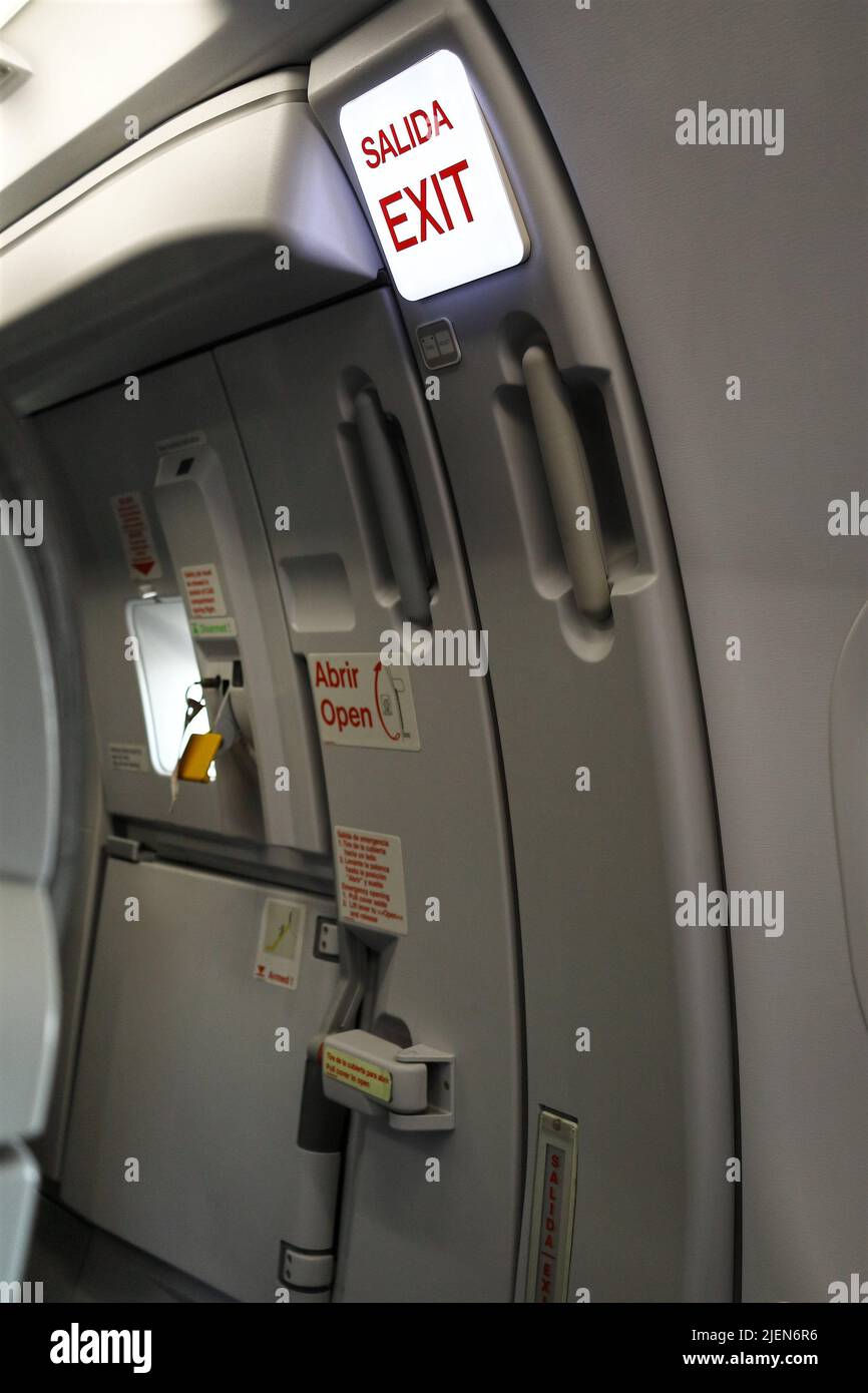 Emergency exit door of an airplane, in English and Spanish Stock Photo