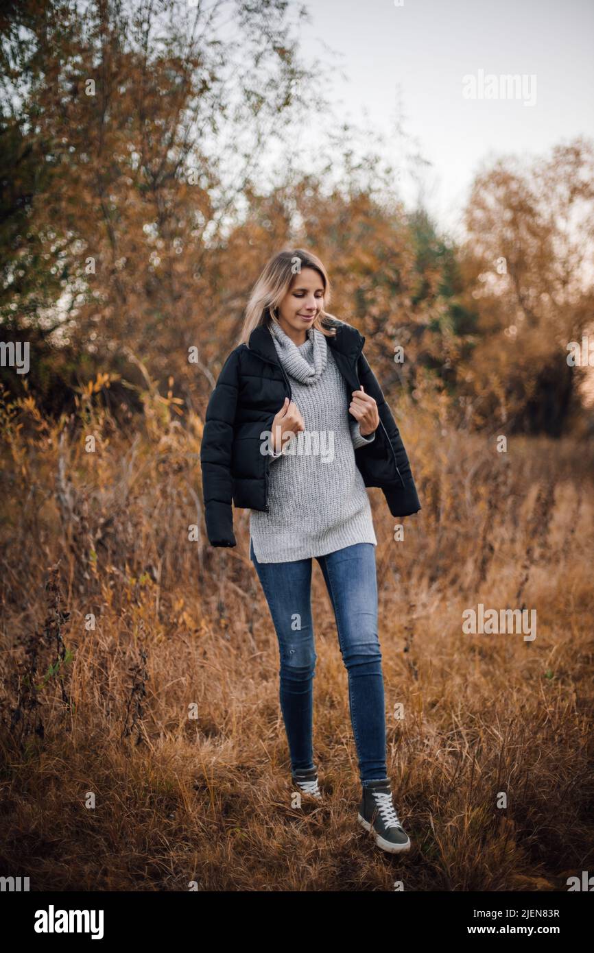 Full-length portrait of young woman walking on grass in meadow in ...