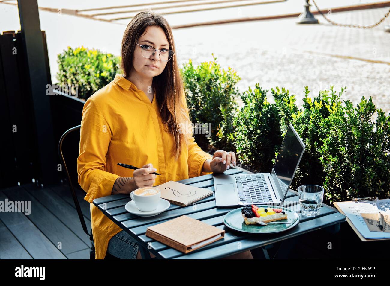 Freelancer problem challenges, Finding work, Finding clients. Freelancer woman working with laptop and writing question mark in notepad while sitting Stock Photo