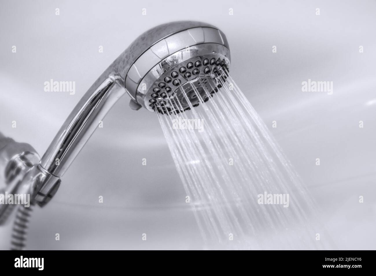 Warm water jet from the head of a handheld shower. Stock Photo