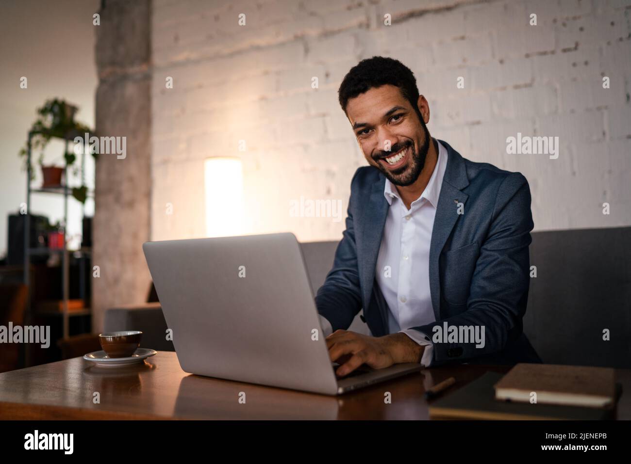 Happy young businessman having coffee and doing his work in cafe. Stock Photo