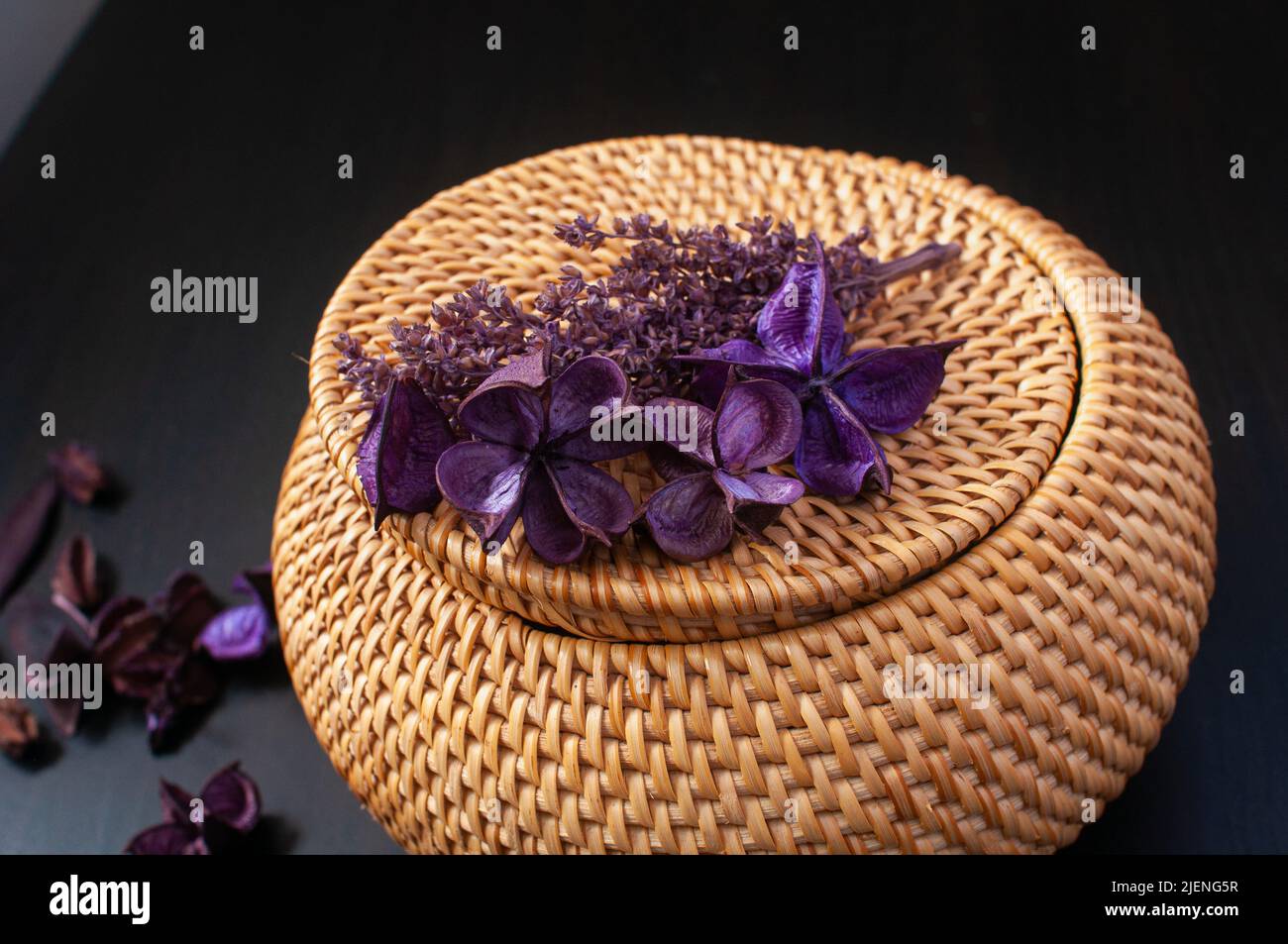 wicker straw box craft round top with dried flowers and lavender on a black background Stock Photo