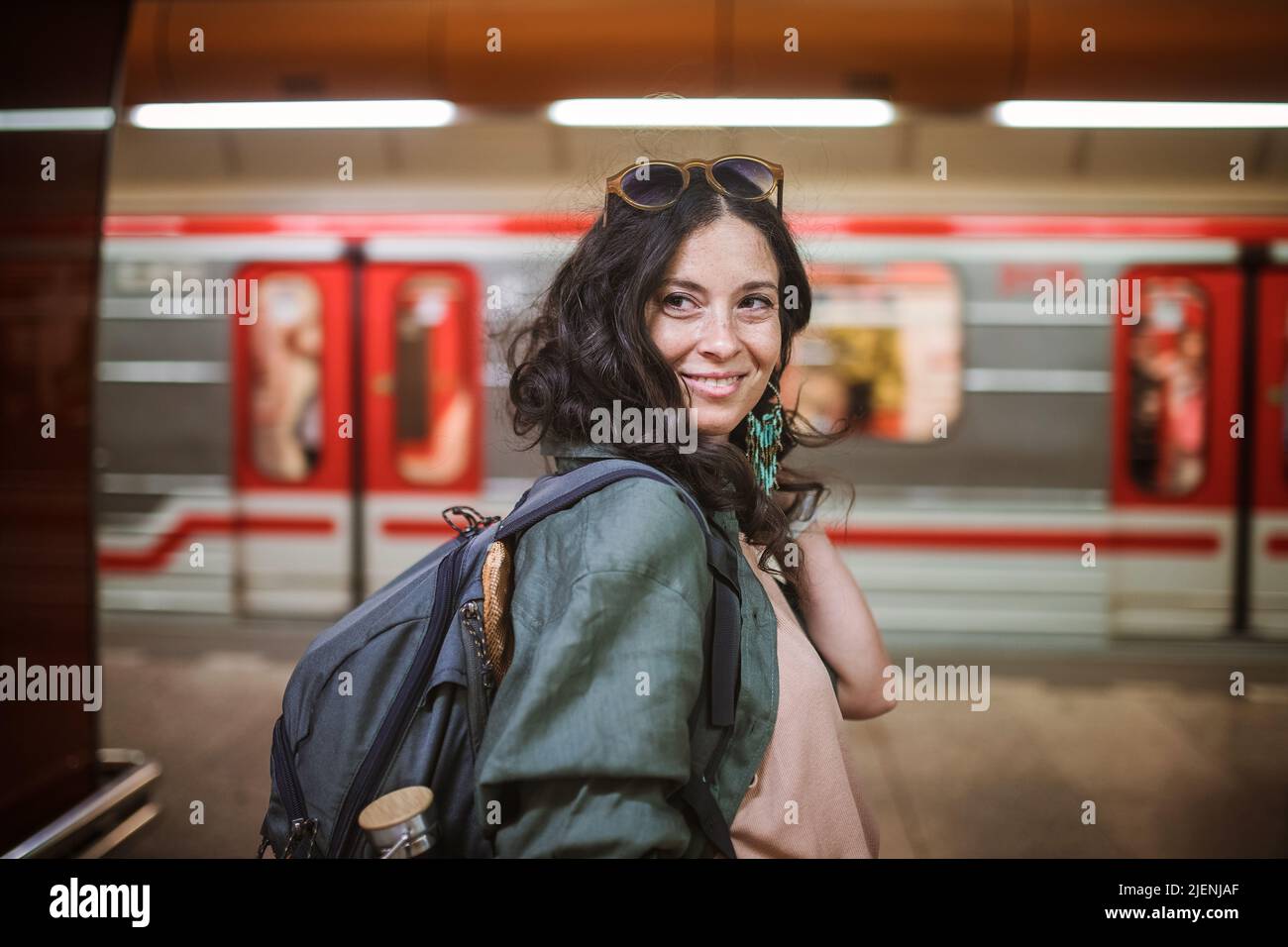 Mid adult woman commuter is standing in subway station and looking at camera. Stock Photo
