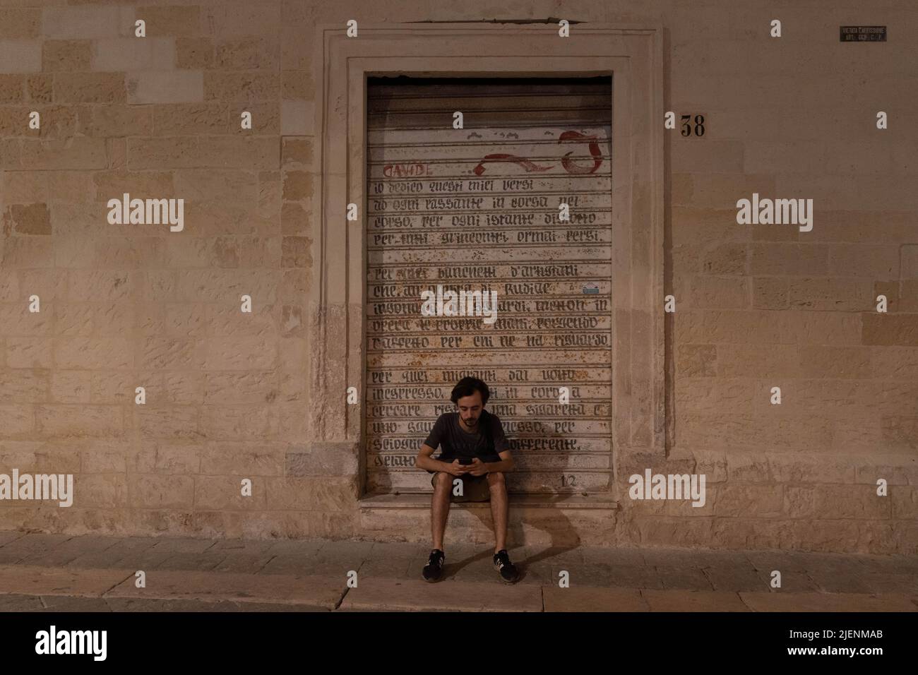 Lecce, Lecce, Italy. 27th June, 2022. A man looks at his cell phone outside a shop in the historic center of Lecce, Italy. (Credit Image: © Matias Basualdo/ZUMA Press Wire) Stock Photo