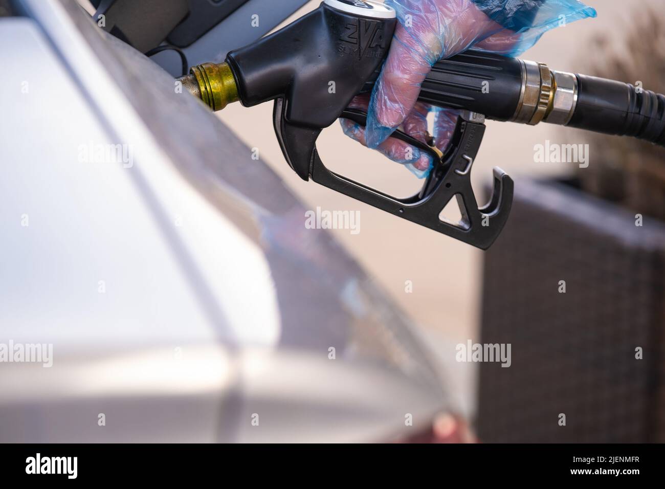 Diesel price in Europe. Refueling the car. pistol in the hands of a man in a blue glove.Car at a gas station. Silver car, refueling pistols .man fills Stock Photo