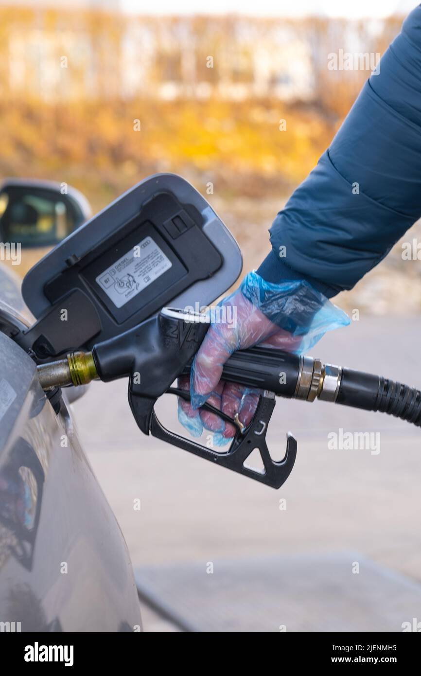 Fuel price in Europe. Refueling the car.Refueling pistol in the hands of a man.Car at a gas station. car, refueling pistols and gloves.man fills up a Stock Photo