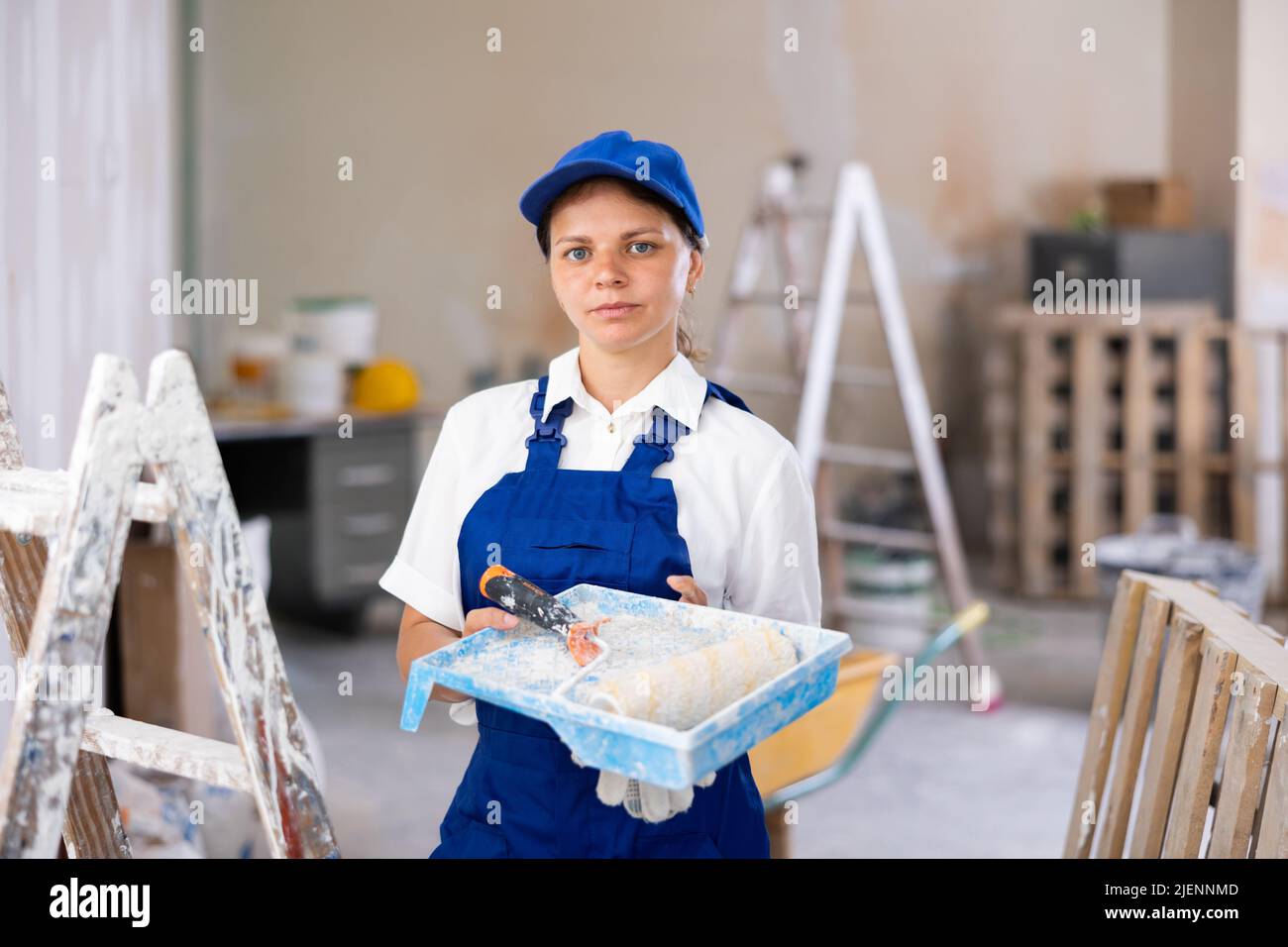 Portrait of female professional painter in blue overall with paint ...