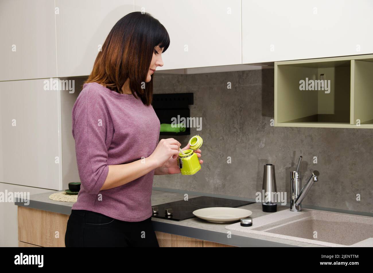 A young woman with a sugar bowl in her hands in the kitchen Stock Photo