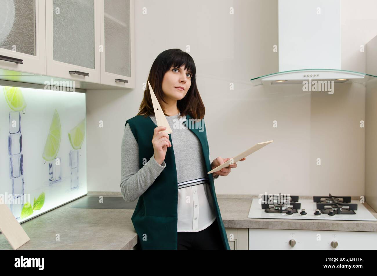 Young woman with a wooden plank next to a gas stove in the kitchen Stock Photo