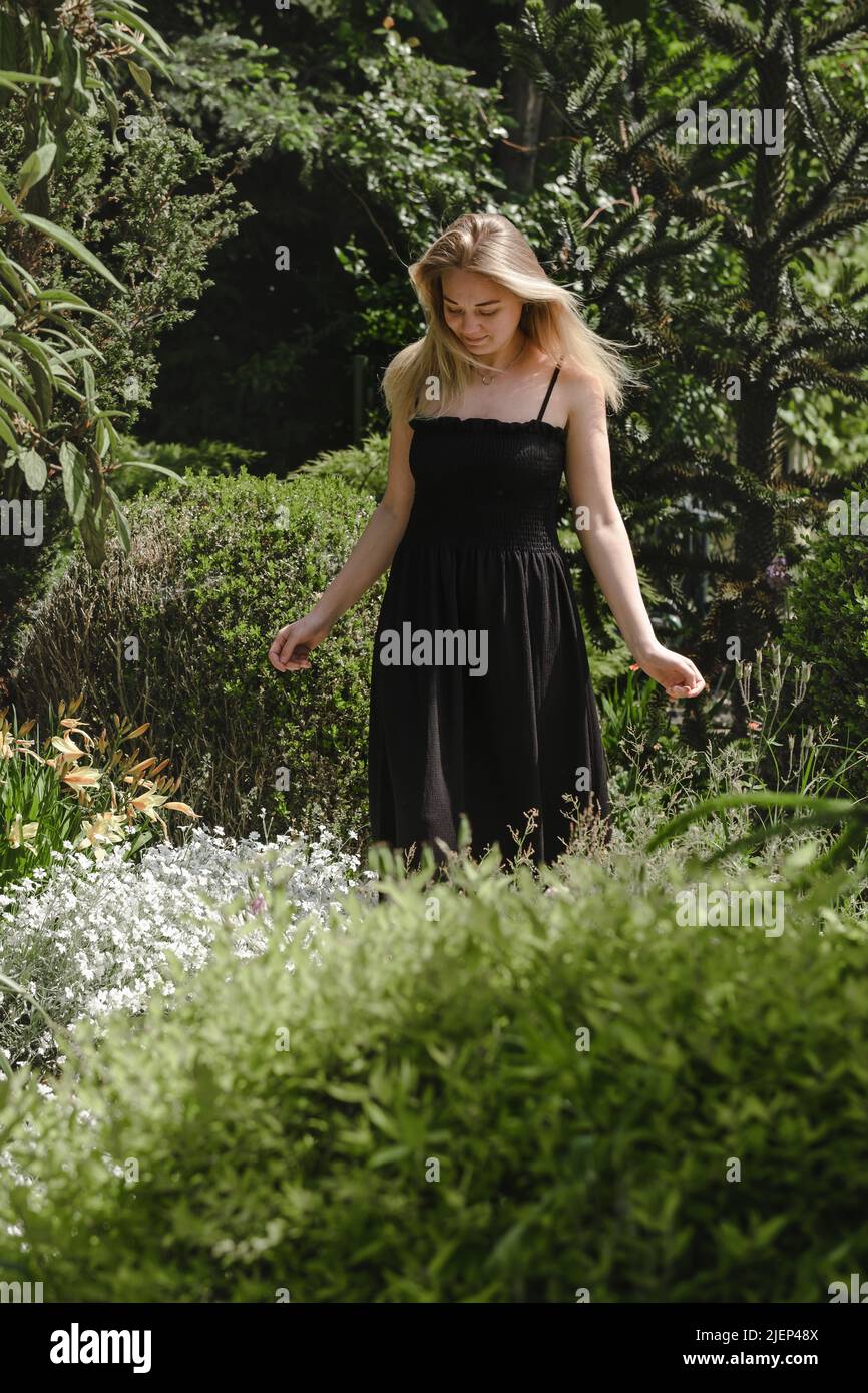 Happy blond woman walking barefoot in the park or garden. Freedom and healthy way of life. Female in her 30s having rest outdoors. People in motion Stock Photo