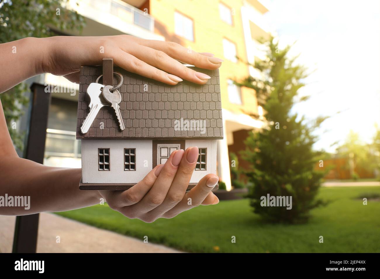 Woman with keys and model of house outdoors Stock Photo - Alamy