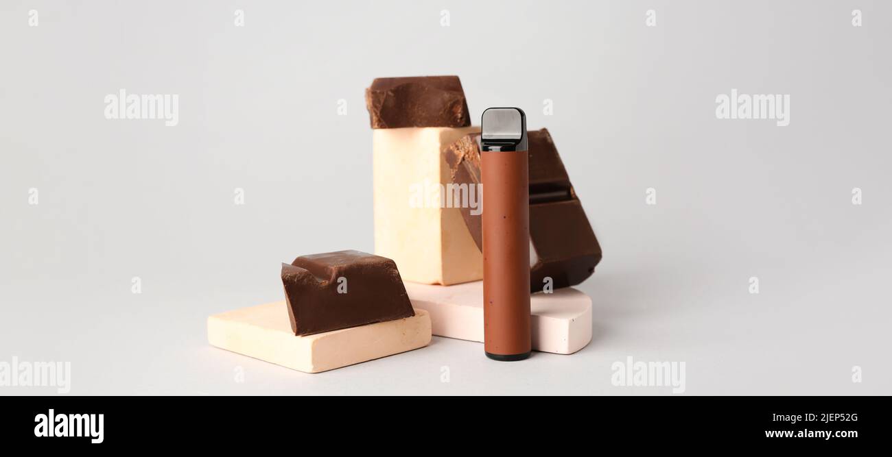 Modern electronic cigarette and chocolate on light background Stock Photo