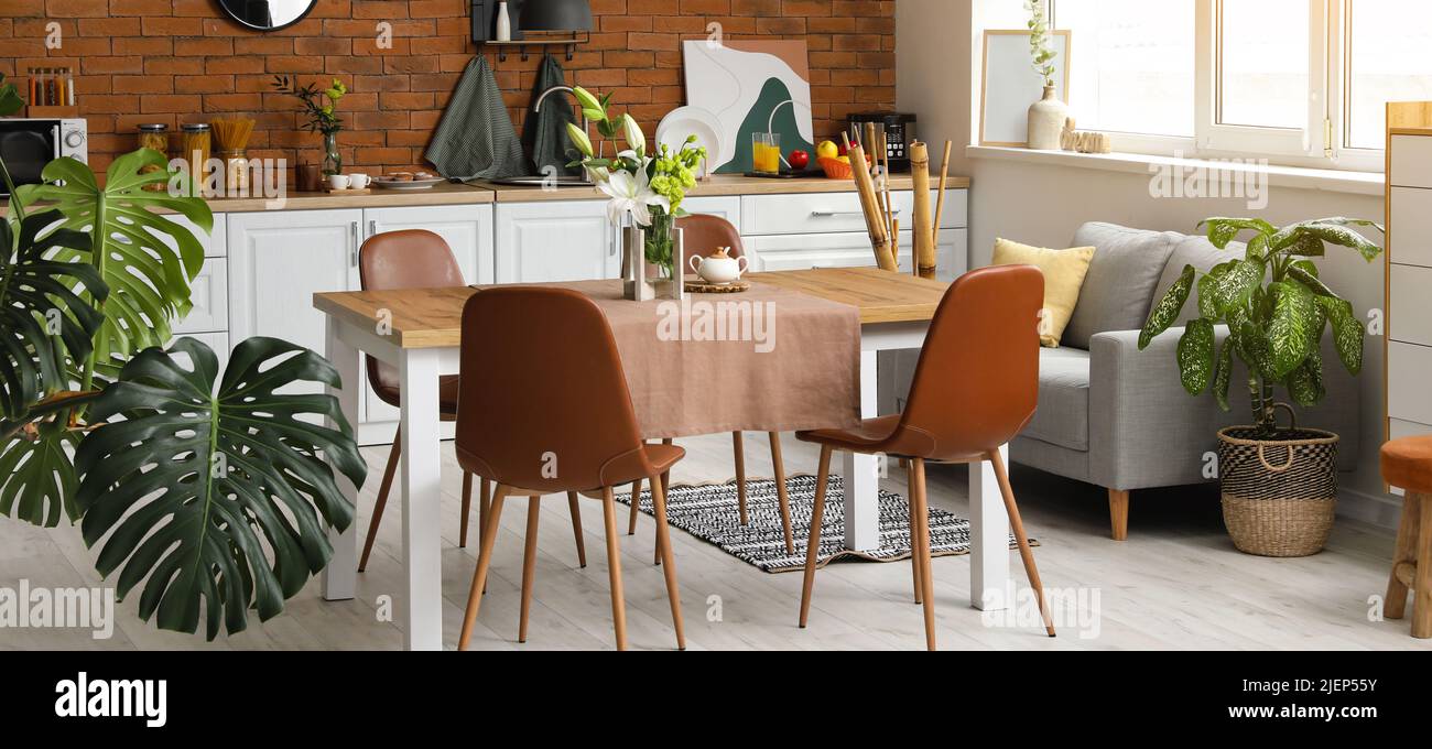 Interior of modern stylish kitchen with dining table and houseplants ...