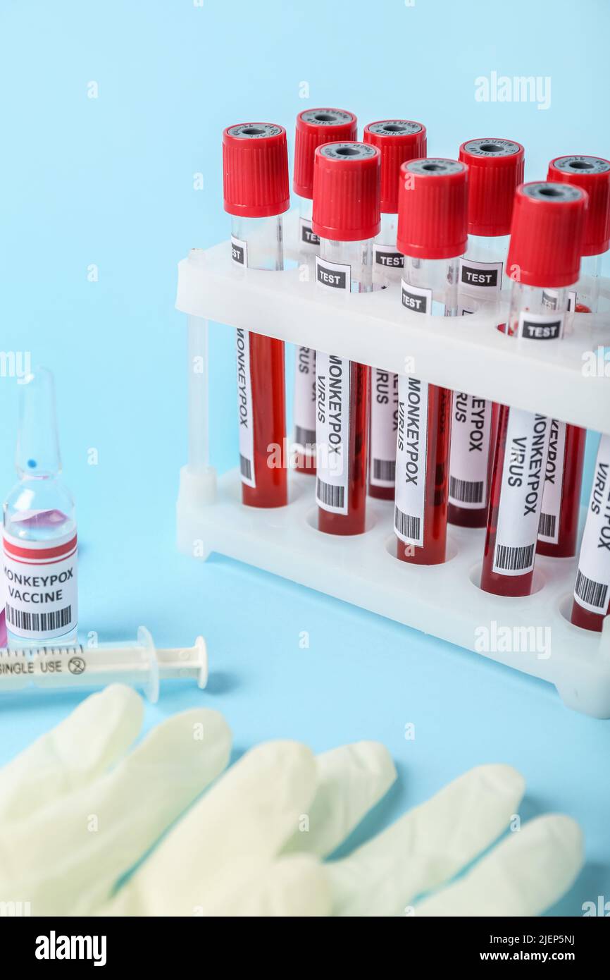 Monkeypox vaccine with syringe and blood samples on blue background ...