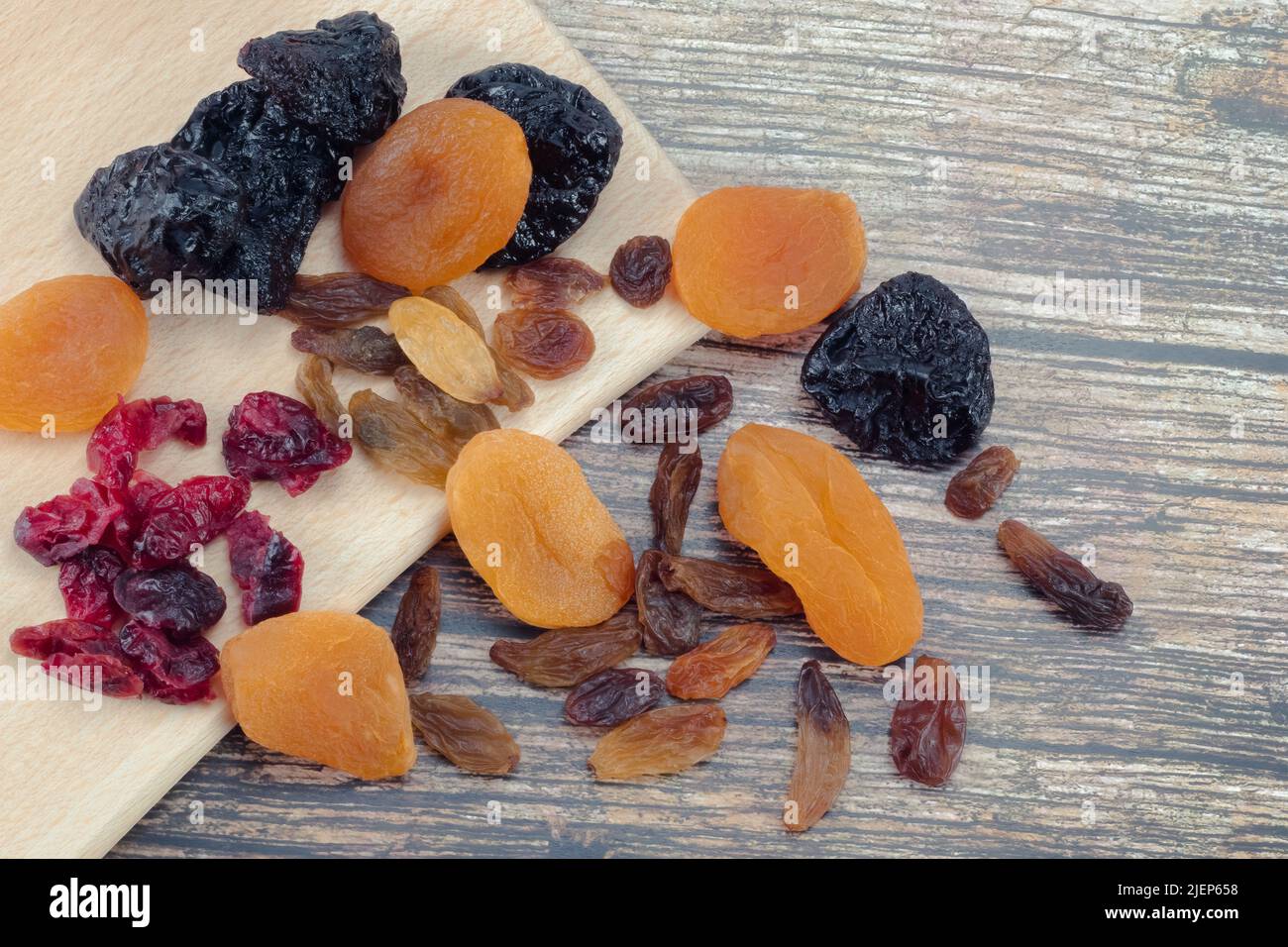 Assortment of dried fruits. Dried plums, apricots, cranberries, grapes on wooden table. Close up view. Stock Photo
