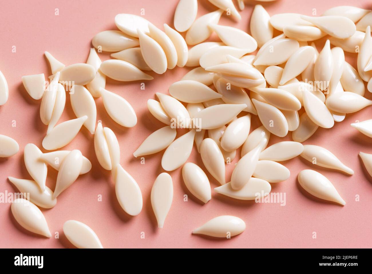 Natural depilatory film wax bean granules on pink background close up. Hair removal, natural beauty concept,  pearl wax. Stock Photo