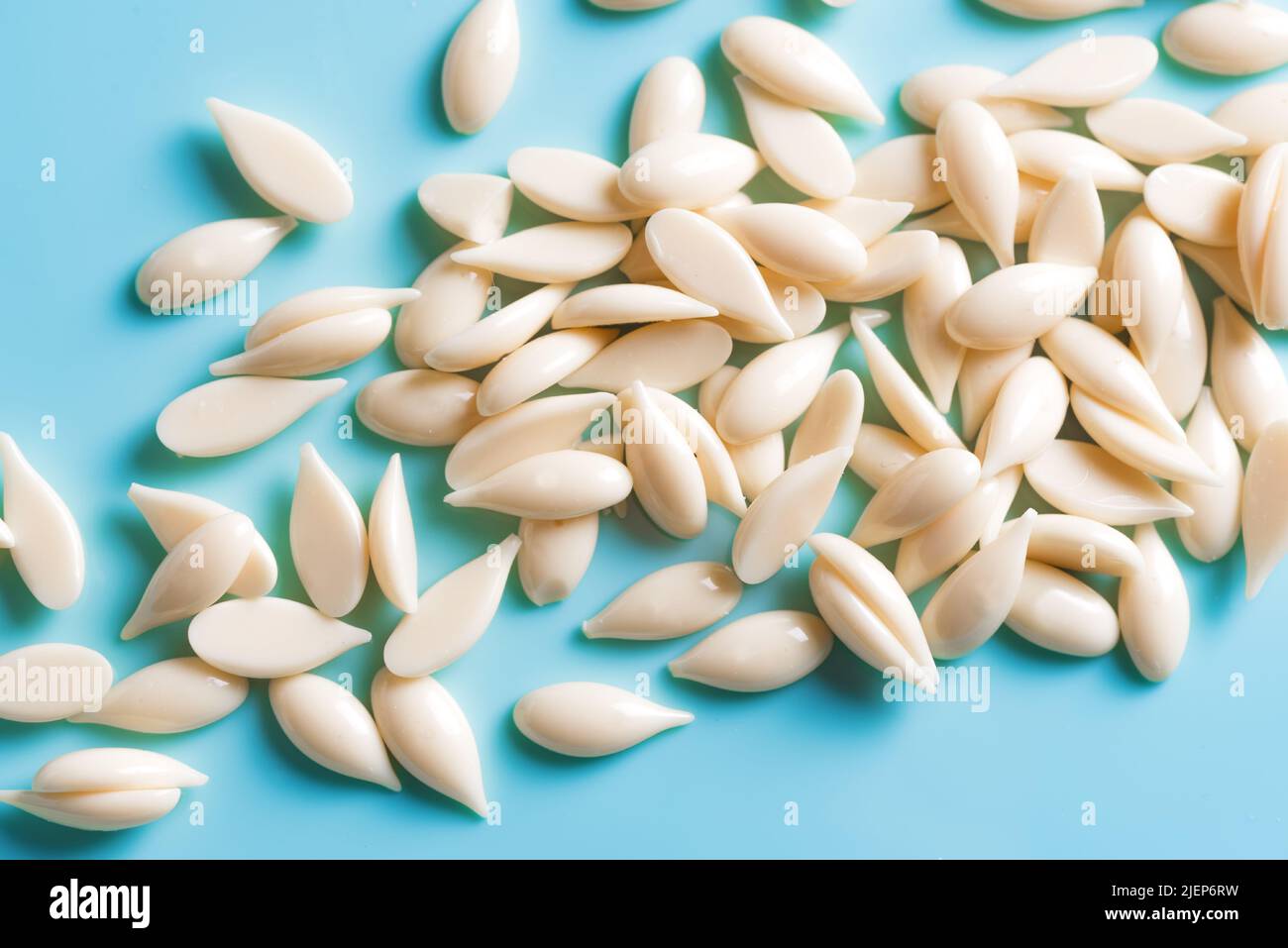 Natural depilatory film wax bean granules on blue background close up. Hair removal, natural beauty concept,  pearl wax. Stock Photo