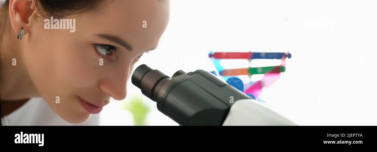 Beautiful woman looks through a microscope, profile view Stock Photo