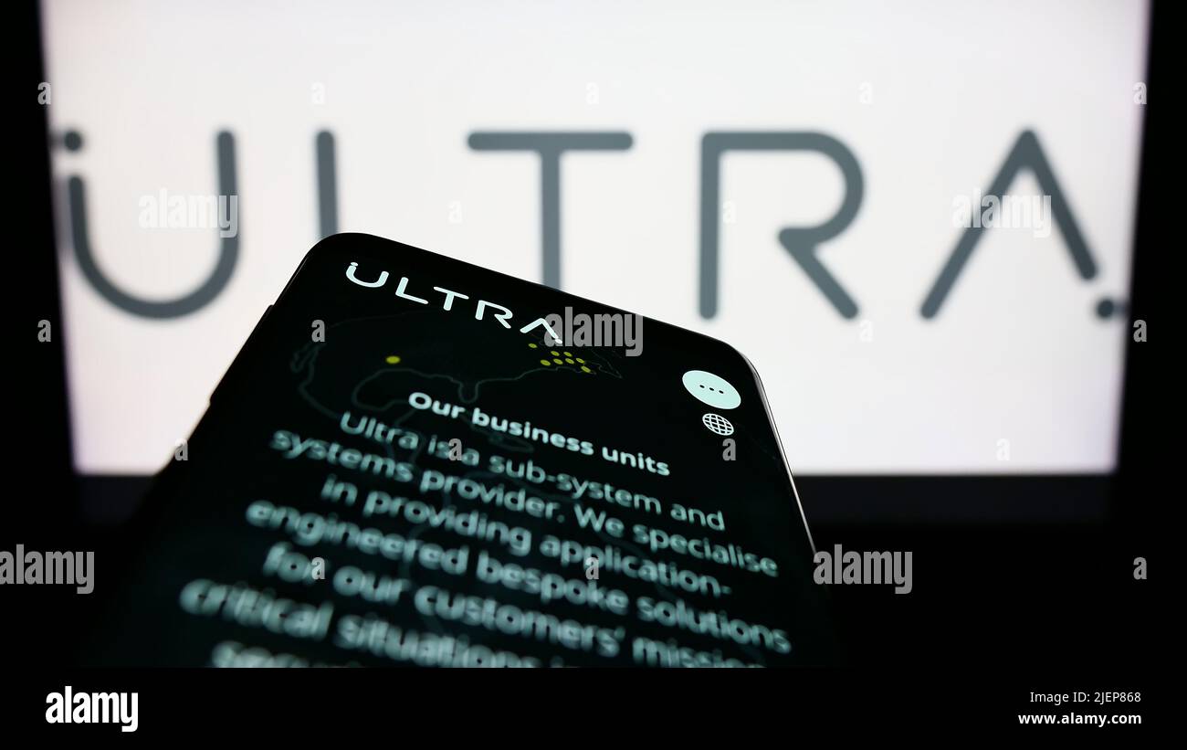 Mobile phone with website of British company Ultra Electronics Holdings plc on screen in front of logo. Focus on top-left of phone display. Stock Photo