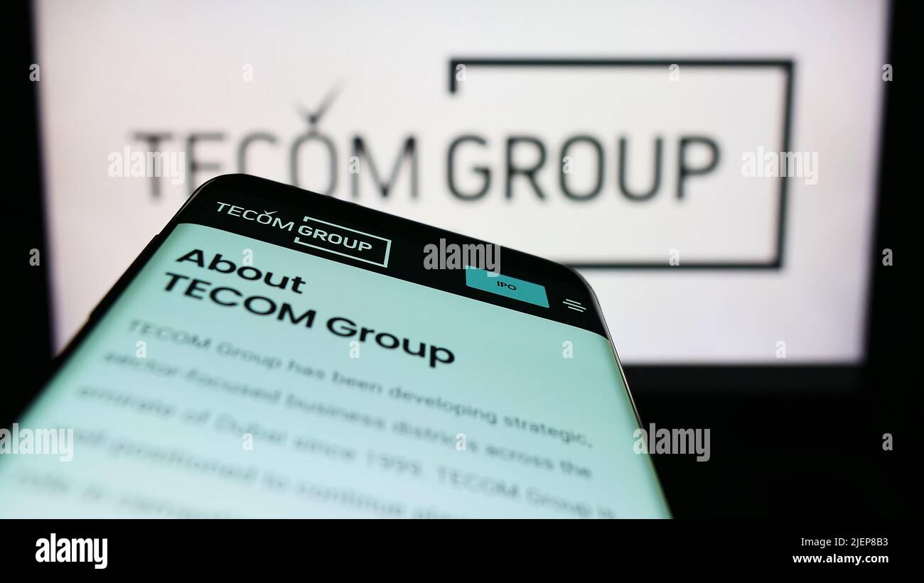 Mobile phone with website of Emirati real estate company Tecom Group LLC on screen in front of business logo. Focus on top-left of phone display. Stock Photo