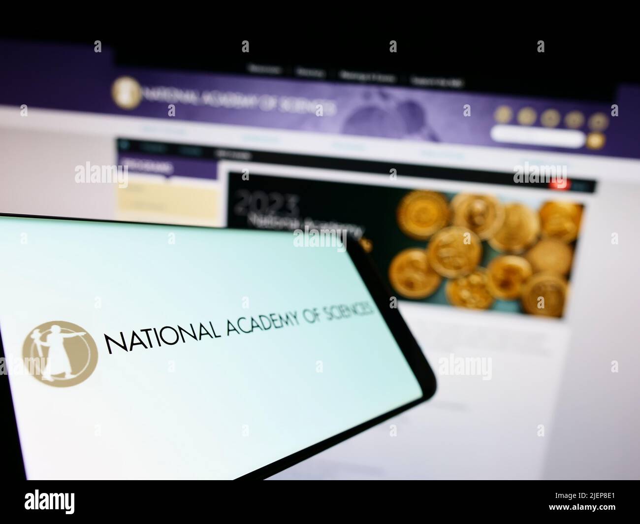 Mobile phone with logo of National Academy of Sciences (NAS) on screen in front of website. Focus on left of phone display. Stock Photo