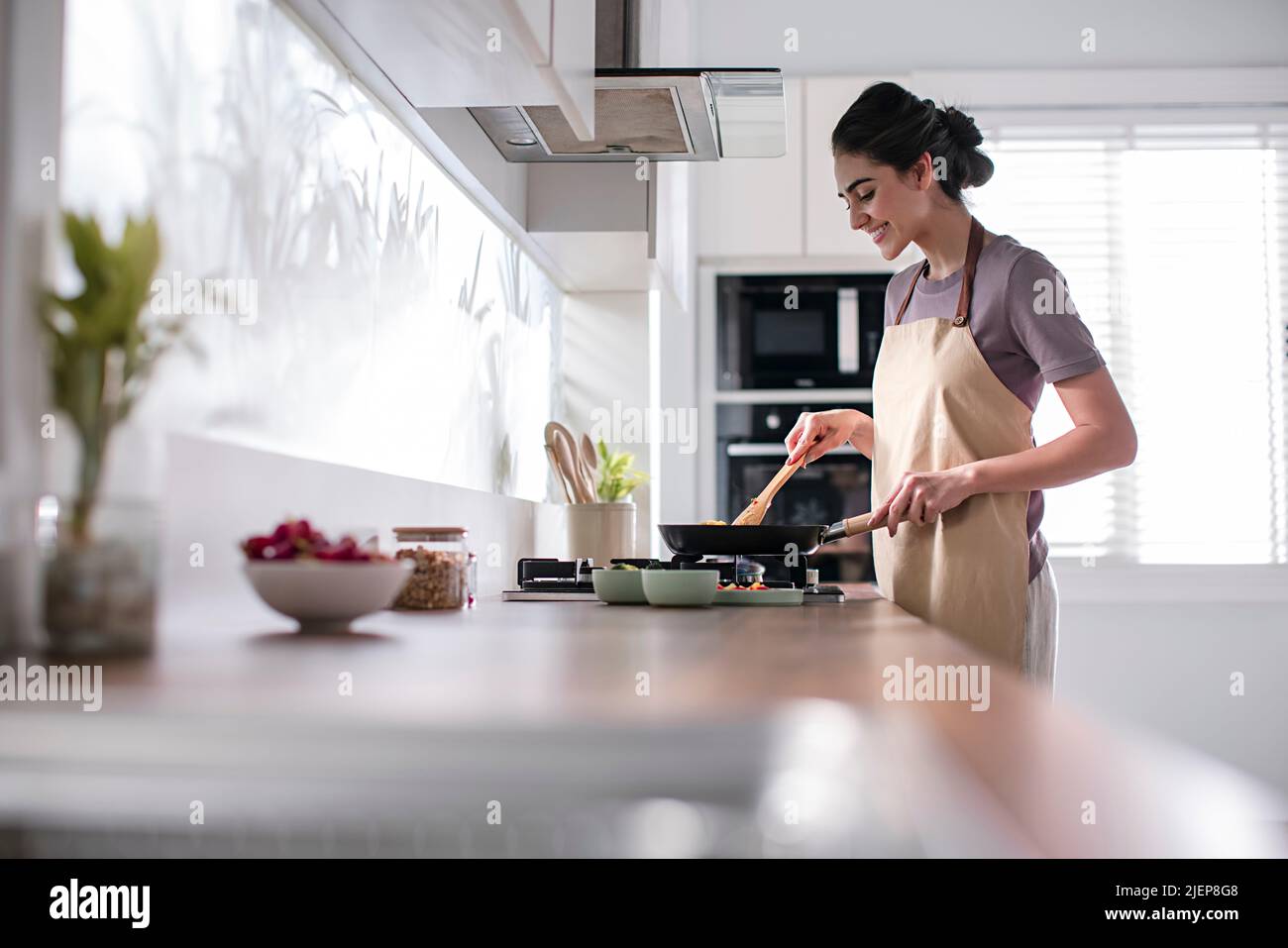Side profile of a young woman cooking food in the kitchen. High quality photo Stock Photo