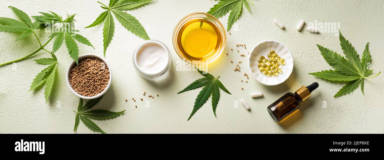 Hemp oil, leaves and products, cbd oil in bottle and capsules, face creme and serum, alternative medicine and organic skin care concept. Banner. Stock Photo