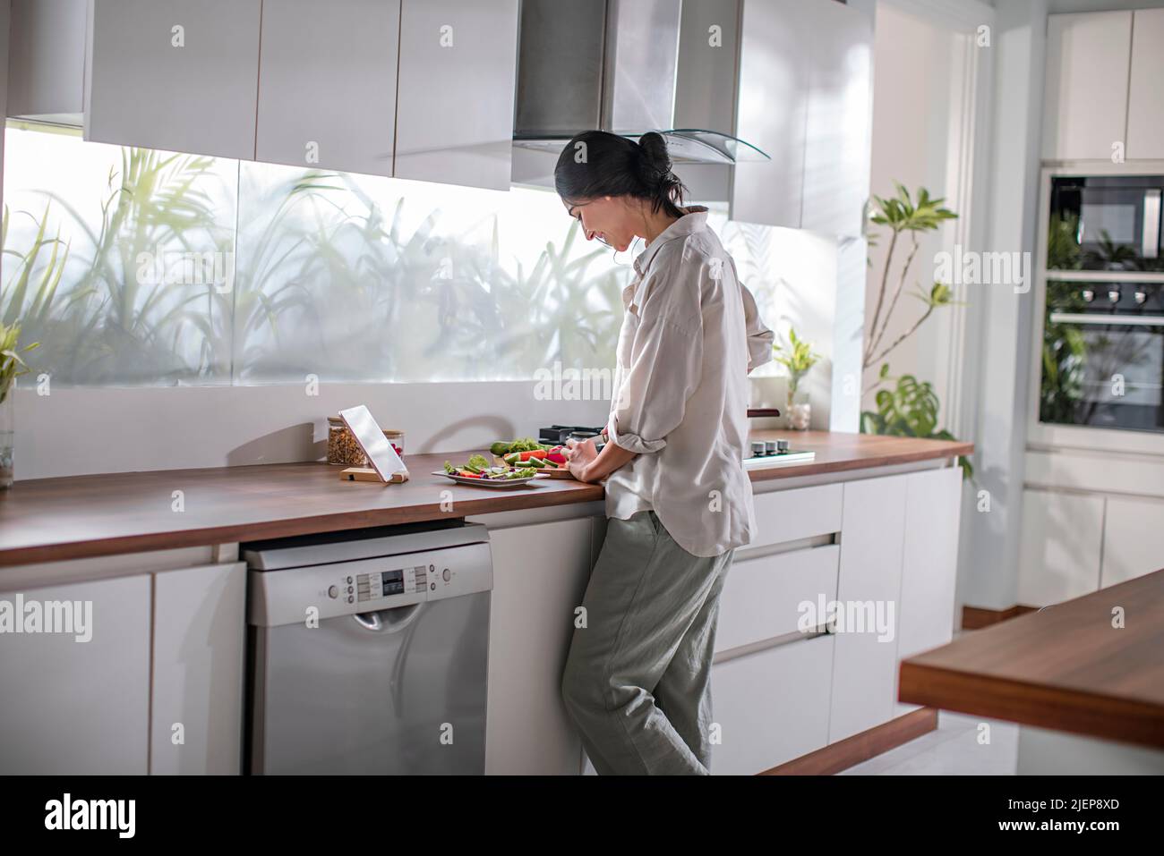 Side profile of a young woman taking cooking classes on the mobile phone Stock Photo