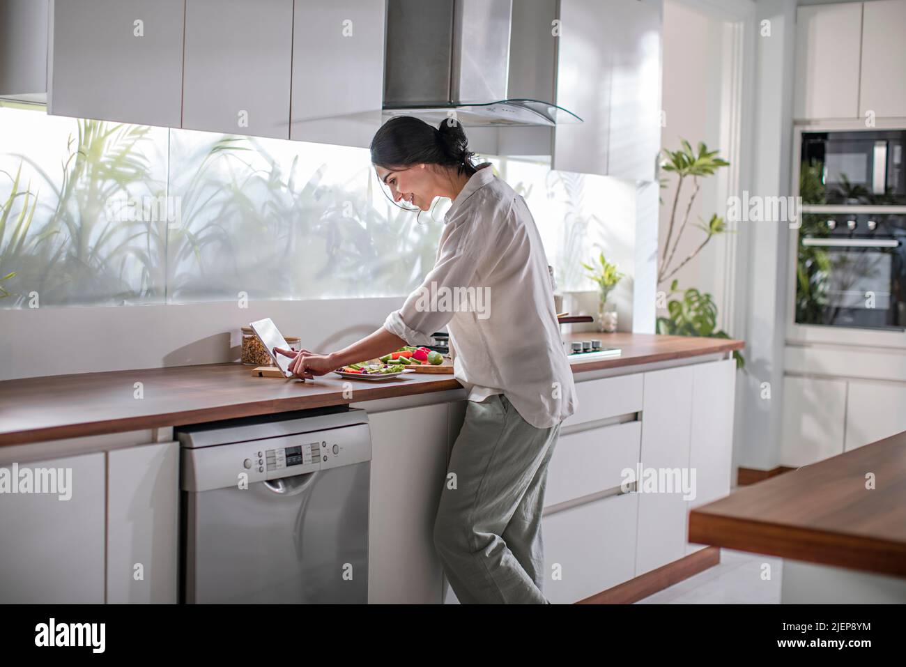 Side profile of a young woman taking cooking classes on the mobile phone Stock Photo