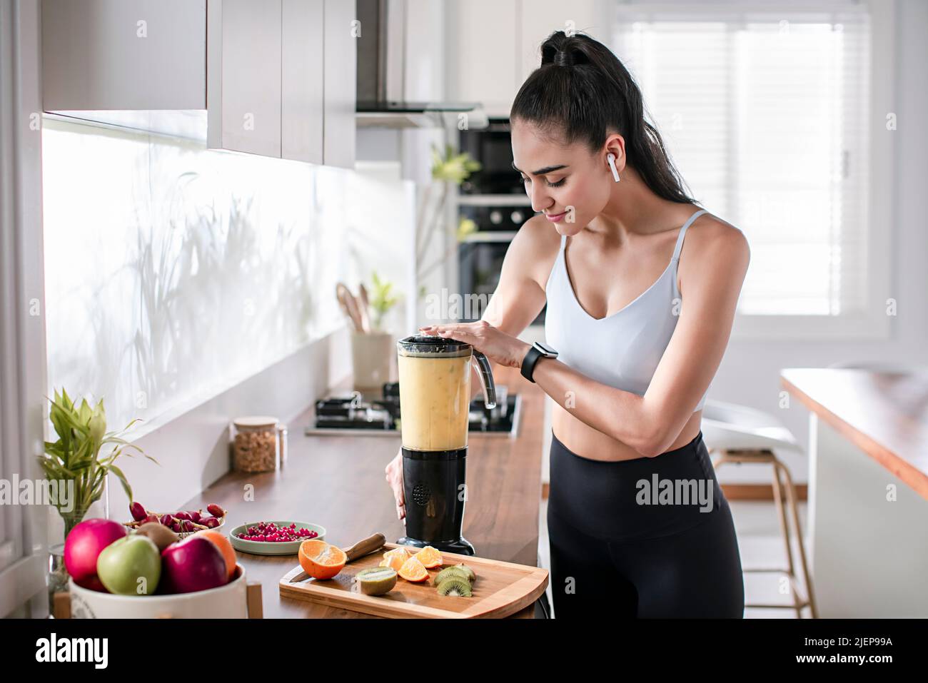 Young woman making milkshake in the kitchen Stock Photo