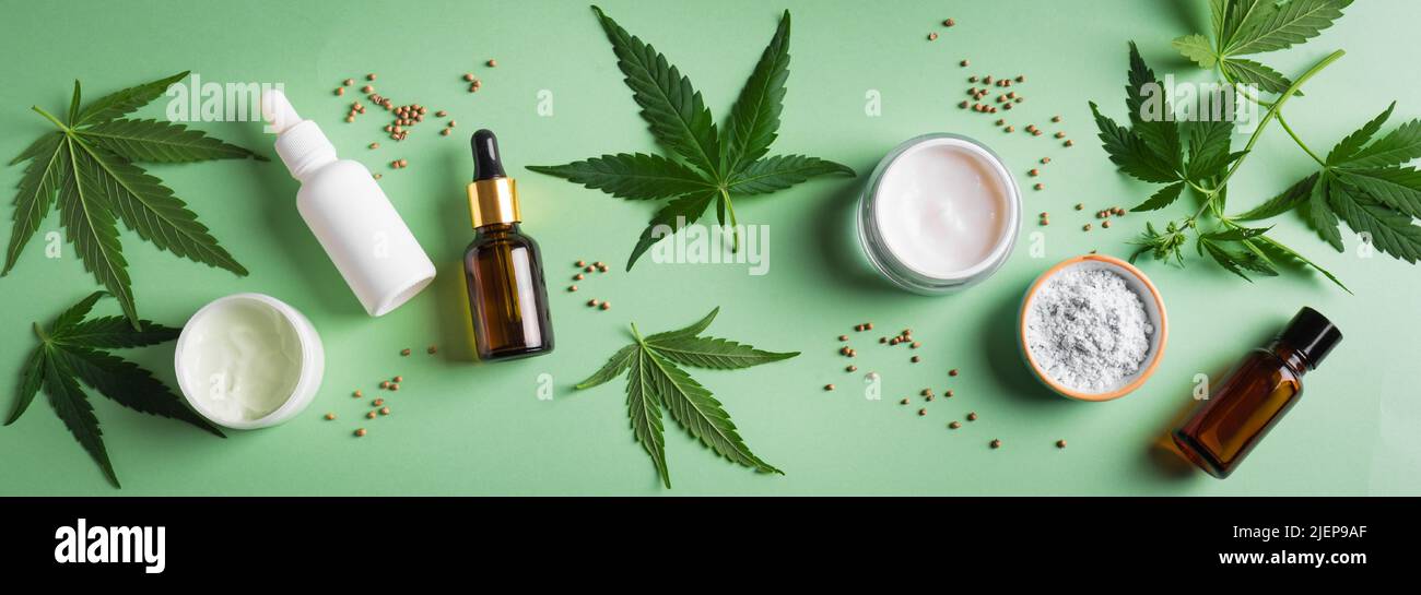 Hemp cannabis  leaves and beauty products, cbd oil in bottle, face creme and serum, alternative medicine and organic skin care concept. Banner. Stock Photo