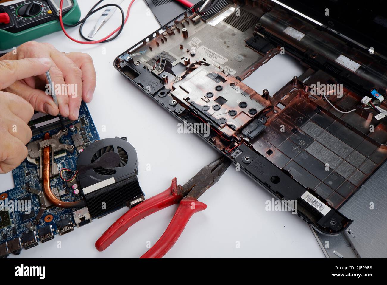 a computer repairman disassembles, repairs and does preventive maintenance for a broken laptop. Stock Photo