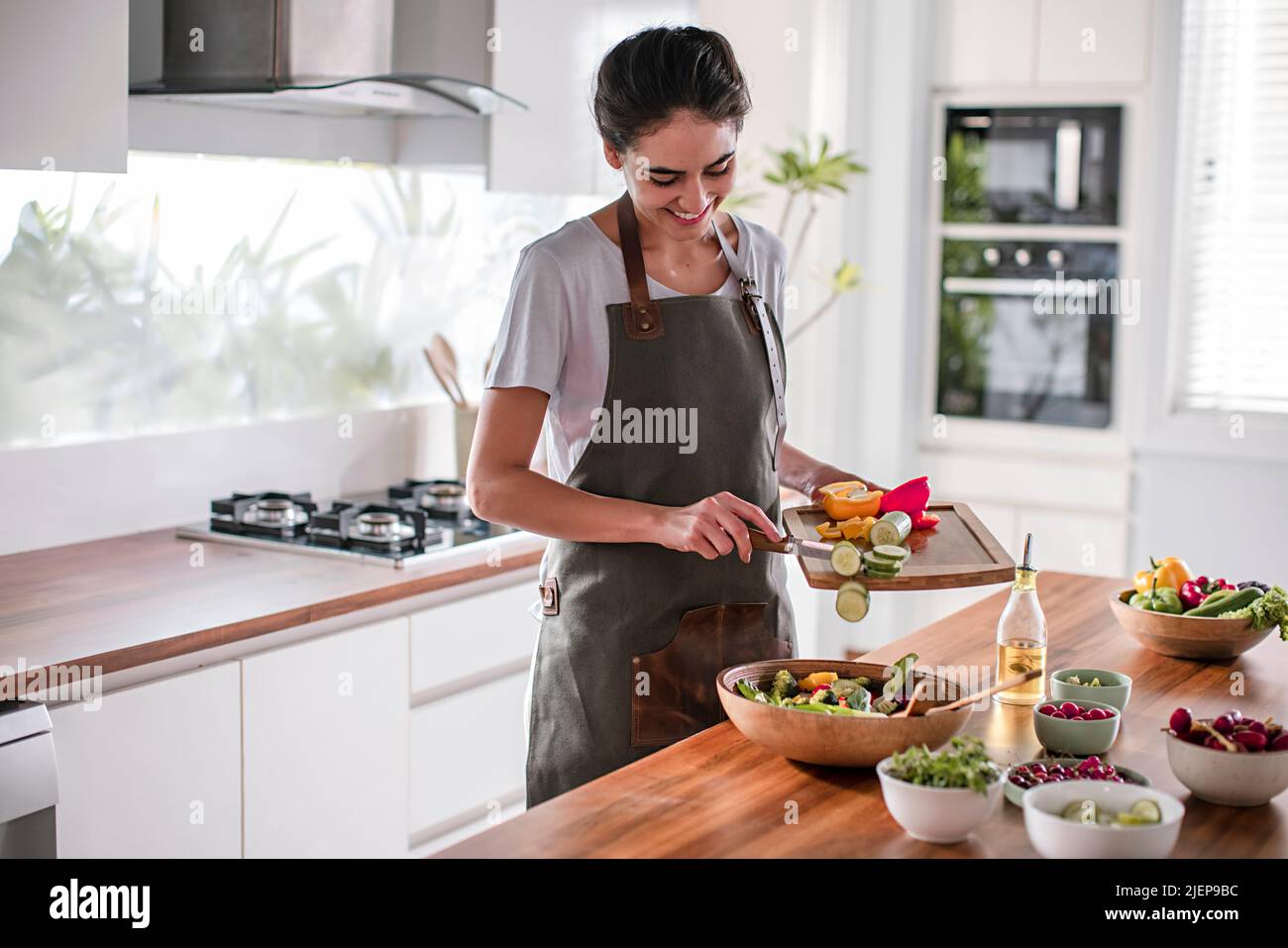 Young woman preparing vegetable salad in the kitchen Stock Photo