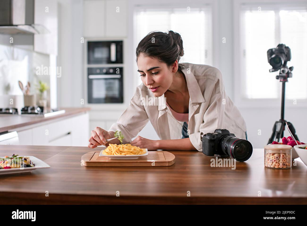 Female food vlogger decorating food in the kitchen Stock Photo