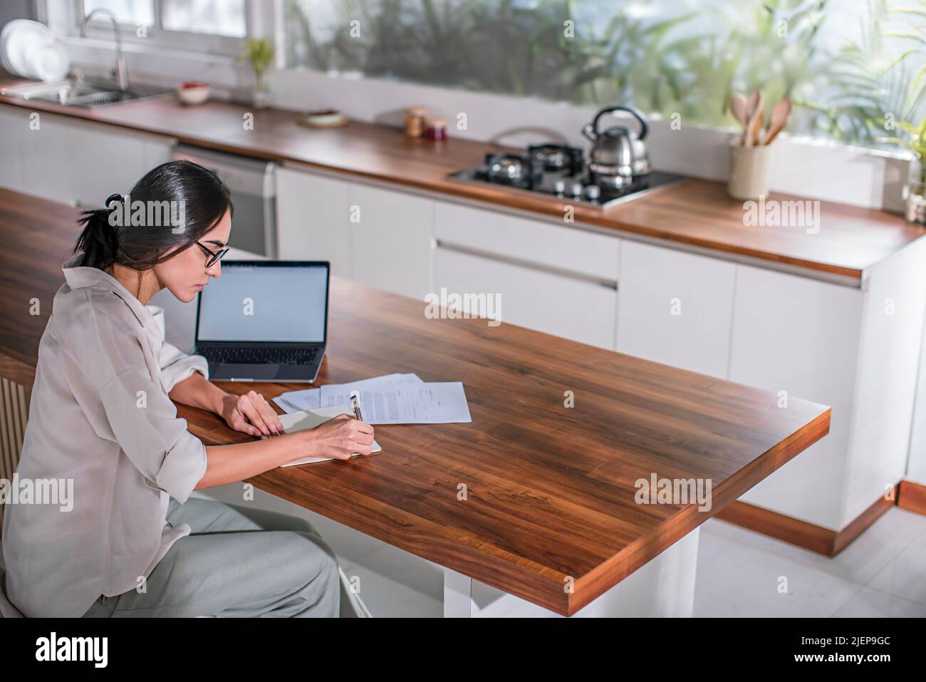Young woman writing on papers at home Stock Photo