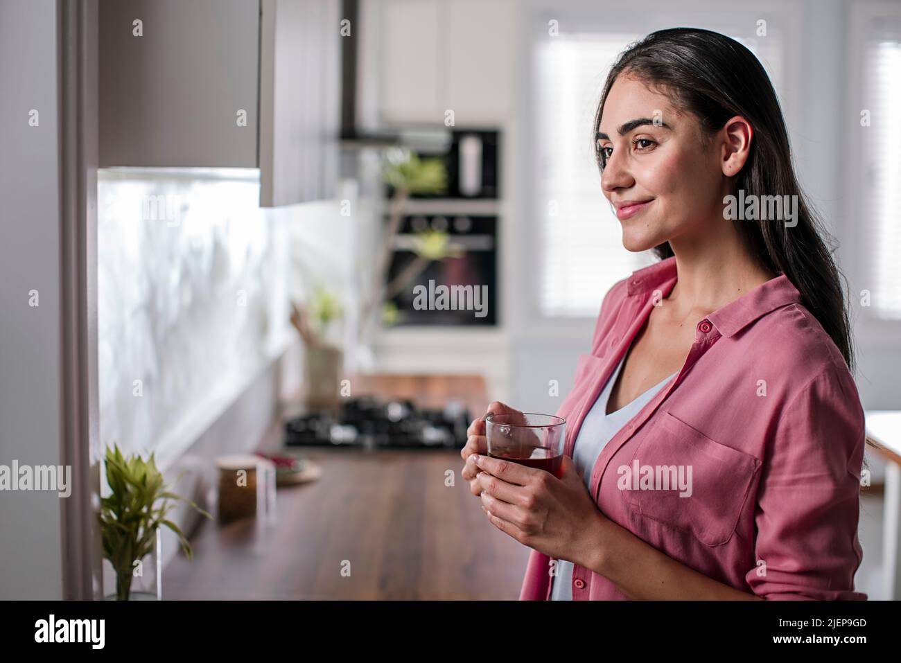 Young woman drinking cup of herbal tea at home Stock Photo