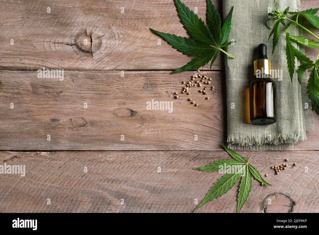 Face serum or cbd oil bottle and hemp plant green leaves on wooden background, copy space. Alternative medicine, cbd oil and organic skin care concept Stock Photo