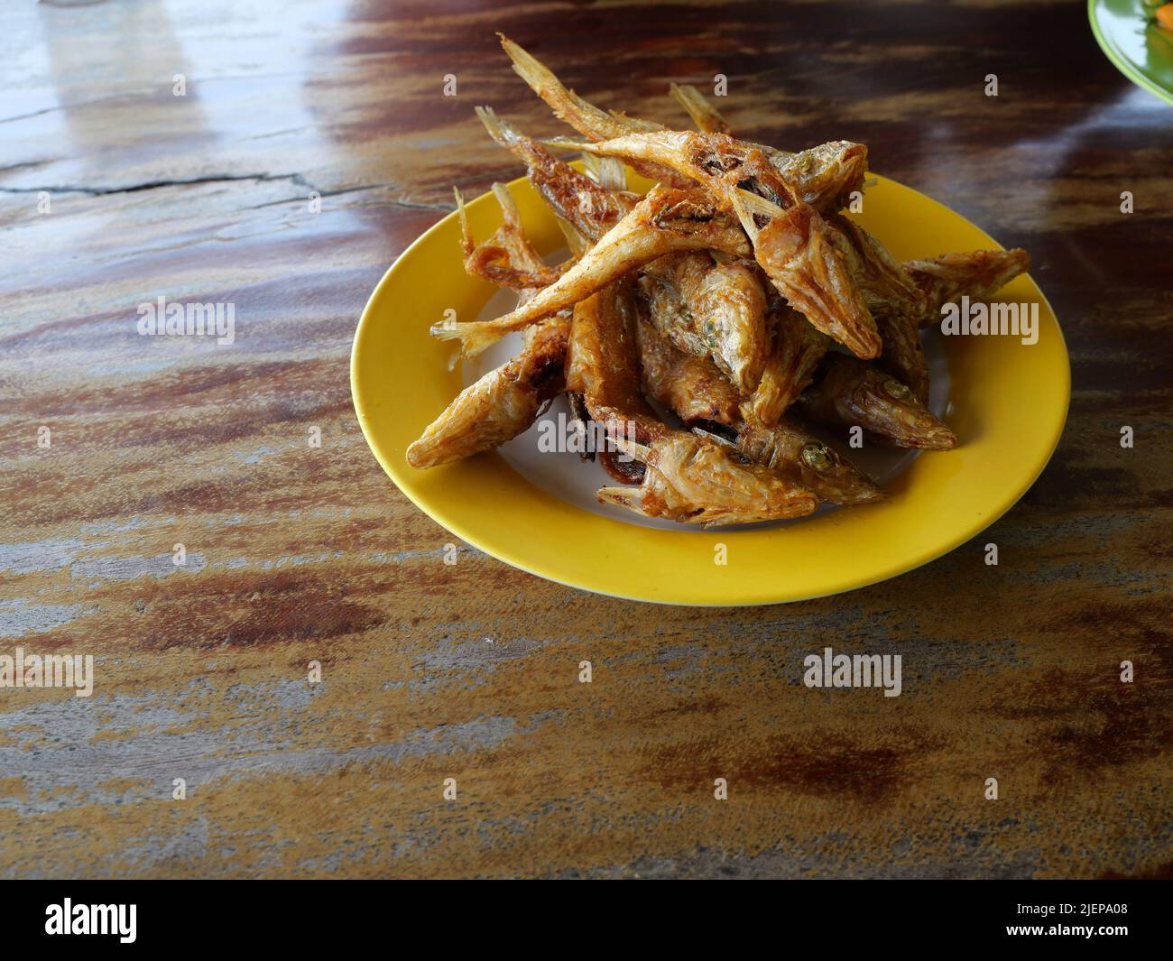 Northern whiting or Silver sillago fish deep fried in yellow dish on brown wooden table, Seafood in Thailand Stock Photo