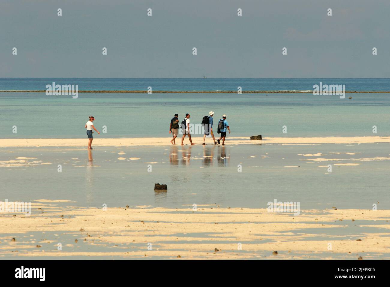 A group of visitors having recreational time during low tide on the flat sandy beach of Sangalaki Island, an island dedicated to sea turtle conservation and a part of of Berau Marine Protected Area within Derawan archipelago in Berau, East Kalimantan, Indonesia. Stock Photo