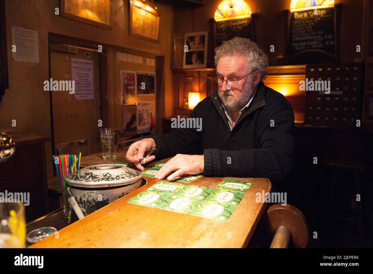 Tilburg, Netherlands. Senior adult male wearing beard and glasses hanging on Weemoed's Bar observing and being the former owner of the cafe establishment. Stock Photo