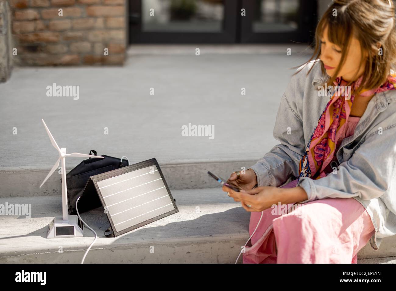 Woman charge phone from a portable solar panel Stock Photo