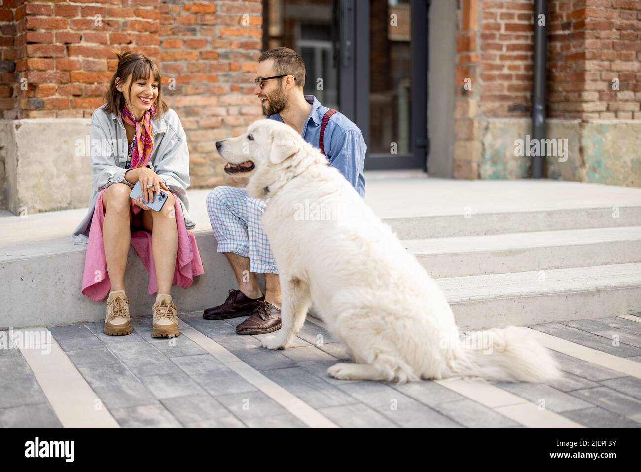 Stylish couple have fun and sit with their dog on a street Stock Photo ...
